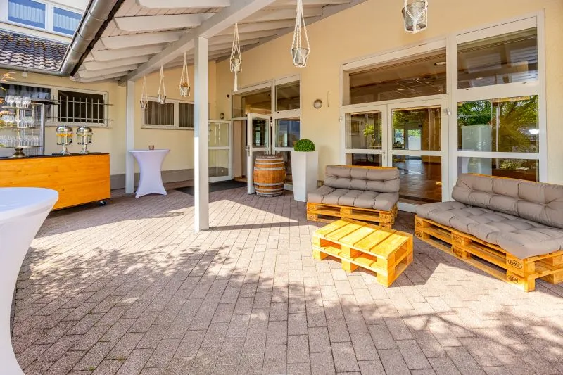 Gemütliche Terrasse mit Palettenmöbeln und Bar für Veranstaltungen im Freien, unter einer überdachten Veranda.