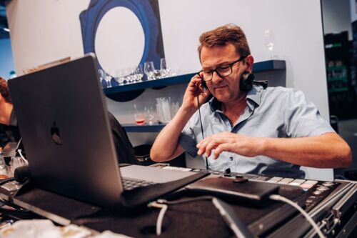 Ein Mann arbeitet mit Laptop und Kopfhörer in einem Büro.